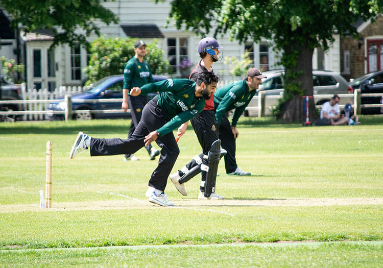 Twickenham CC player mid-bowl with other players in background