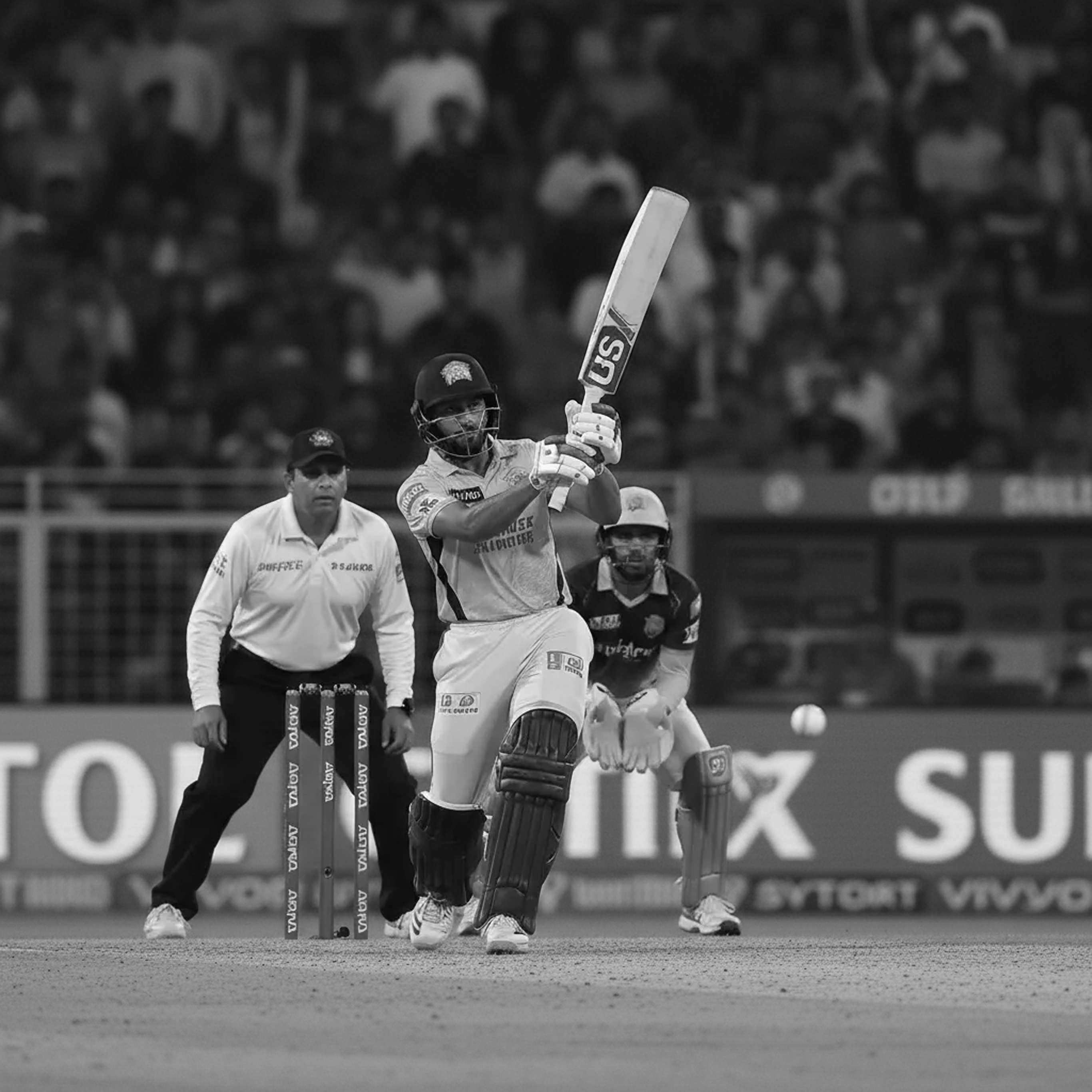 Black and white shot of three pro cricketers with the batter mid-bat.