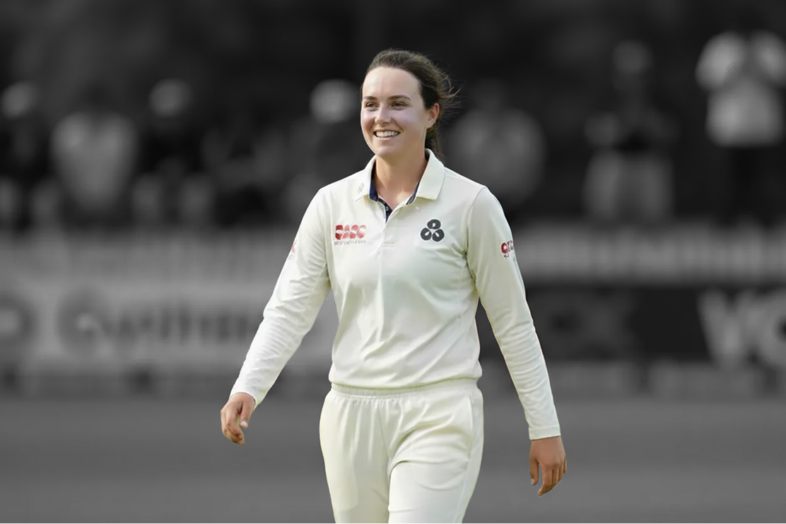 Female cricketer in club whites walking through grounds