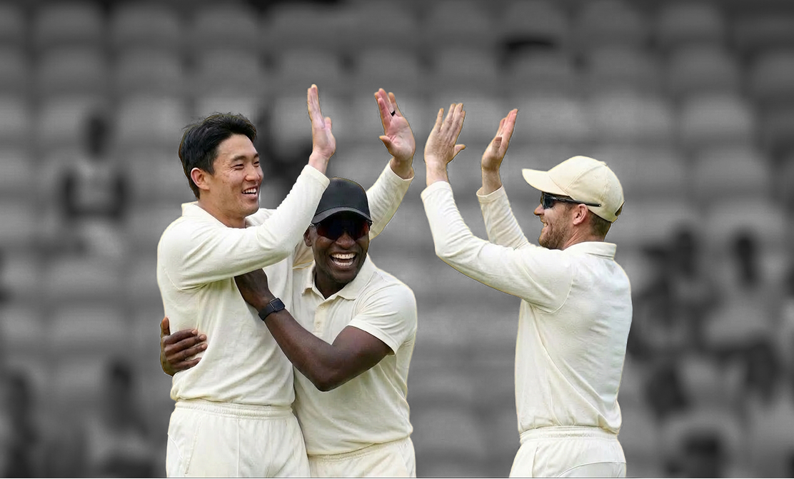 Three cricket teammates celebrating after a win, two high-fiving.